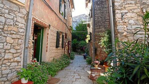 A narrow stone alley with a restaurant named "Castel" on the left, featuring a green door and outdoor seating with potted plants. - 5 star holiday home in the old town of Bale (Bale)