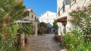 A narrow cobblestone street flanked by stone buildings with shutters, lush greenery, and a clear blue sky. - 5 star holiday home in the old town of Bale (Bale)