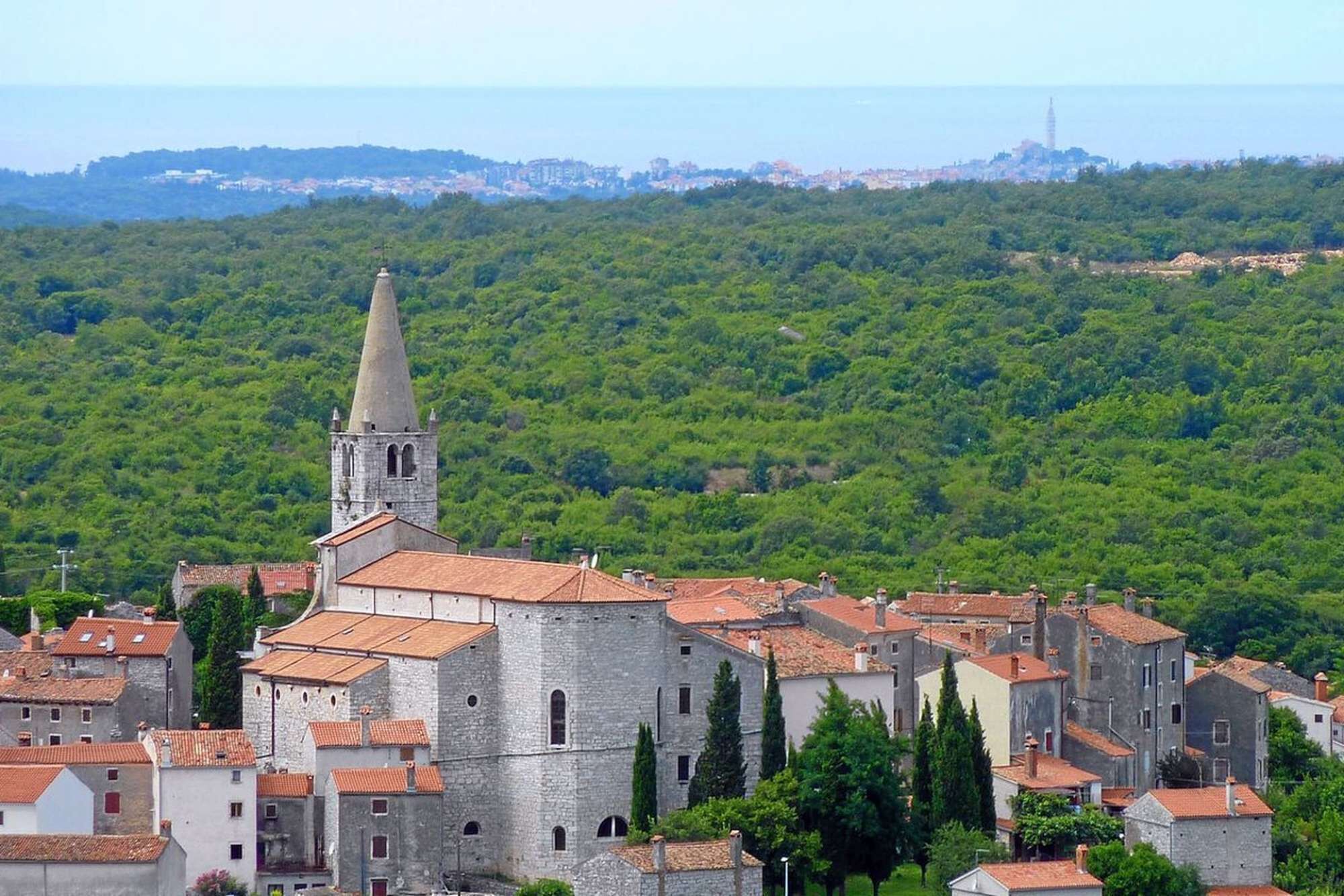 Una cittadina storica con edifici in pietra e un'imponente torre campanaria.