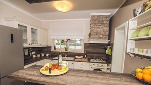 Una cocina moderna con armarios blancos, salpicadero de piedra y encimera de madera.