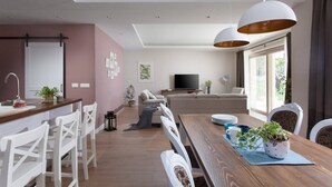 Una sala de estar moderna con comedor, televisor y un ventanal grande.