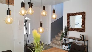 Un comedor moderno con una mesa de madera, lámparas colgantes y una escalera.