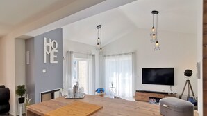 Una cocina moderna con una isla de madera, luces colgantes, un televisor de pantalla plana y un proyector montado sobre un trípode.