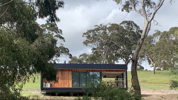 A modern cabin with large windows, surrounded by trees and a grassy field. - Ironbark Luxury Retreat at Softfoot Alpaca Farm in Victor Harbor (Hindmarsh Valley)