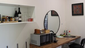 A compact kitchen with a microwave, sink, and a shelf with various bottles and glasses. - Ironbark Luxury Retreat at Softfoot Alpaca Farm in Victor Harbor (Hindmarsh Valley)
