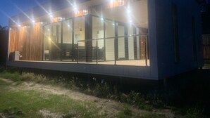 A modern house with a large glass front, wooden exterior, and a visible staircase leading to the upper level. - Ironbark Luxury Retreat at Softfoot Alpaca Farm in Victor Harbor (Hindmarsh Valley)