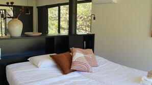 A neatly made bed with white bedding, a vase with dried flowers, and a bowl on a shelf above the bed. - Ironbark Luxury Retreat at Softfoot Alpaca Farm in Victor Harbor (Hindmarsh Valley)