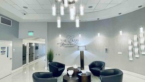 A modern lobby with a central seating area, a large illuminated sign, and a clean, tiled floor. - Partial Ocean 3 Beds -1 bath  Brickell @ownpm10 (Miami)