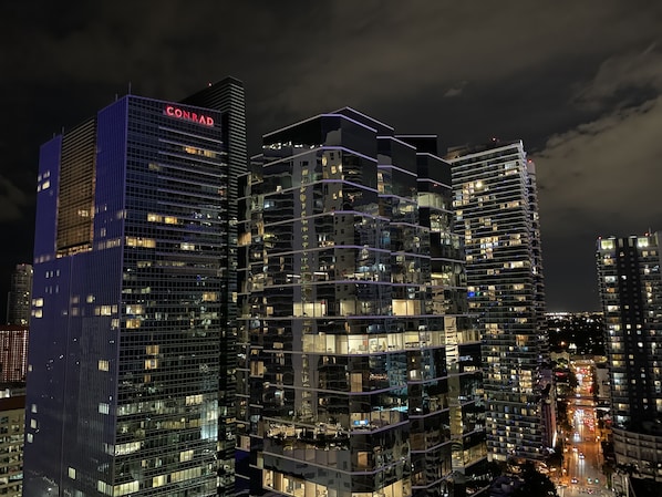 A modern high-rise building with multiple floors, large windows, and a prominent 'CONRAD' sign at the top.