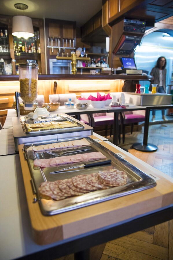 Una barra de buffet con diferentes opciones de comida, una zona de bar con botellas y un área de estar con mesas y sillas.