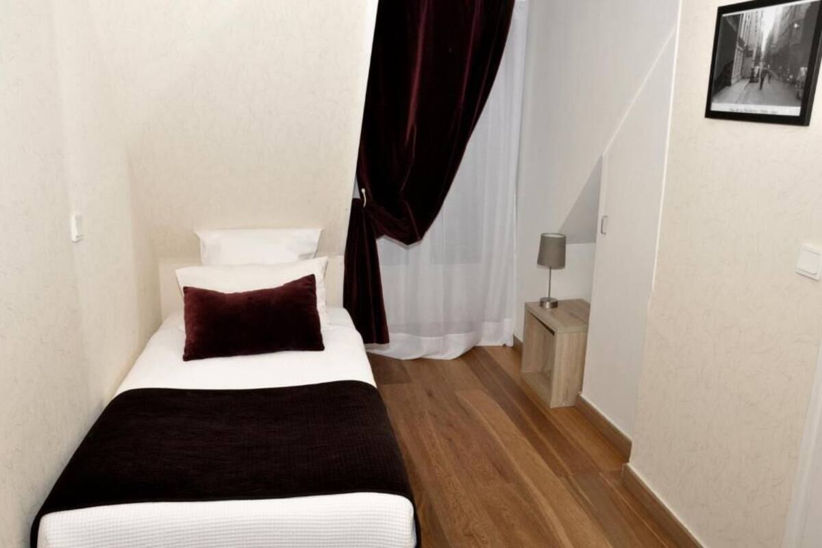 A small, neatly arranged bedroom with a bed, a nightstand, and a lamp.
