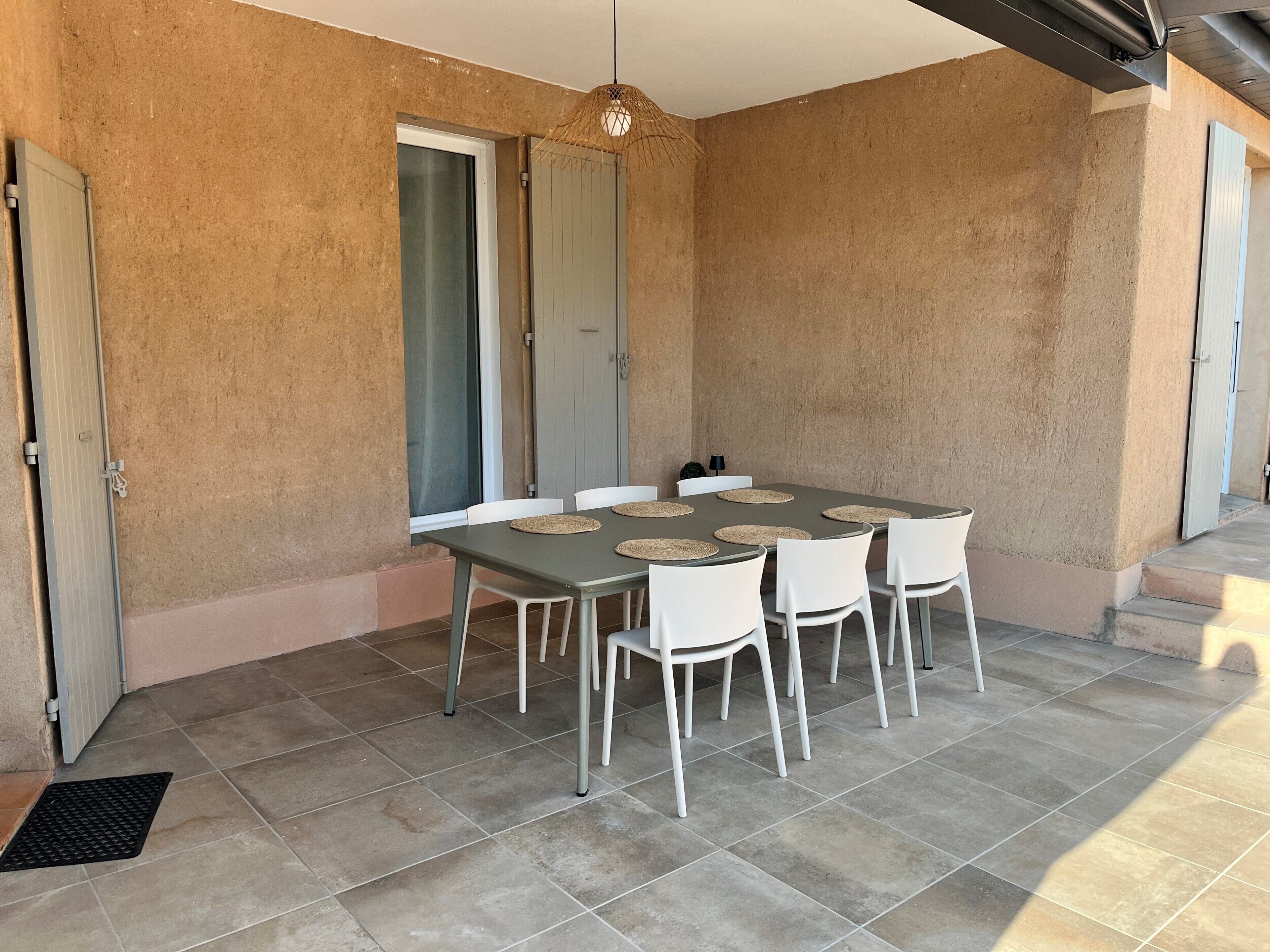 A dining area with a table and chairs, a hanging light fixture, and a door.