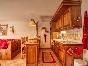 Une cuisine chaleureuse avec des meubles en bois, une table à manger et un canapé rouge.