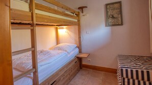 A bunk bed room with a wooden headboard, a small bedside table, and a wall-mounted light. - Lovely 3-bed apartment, mountain decor, ski-in/ski-out (Morillon 1100)