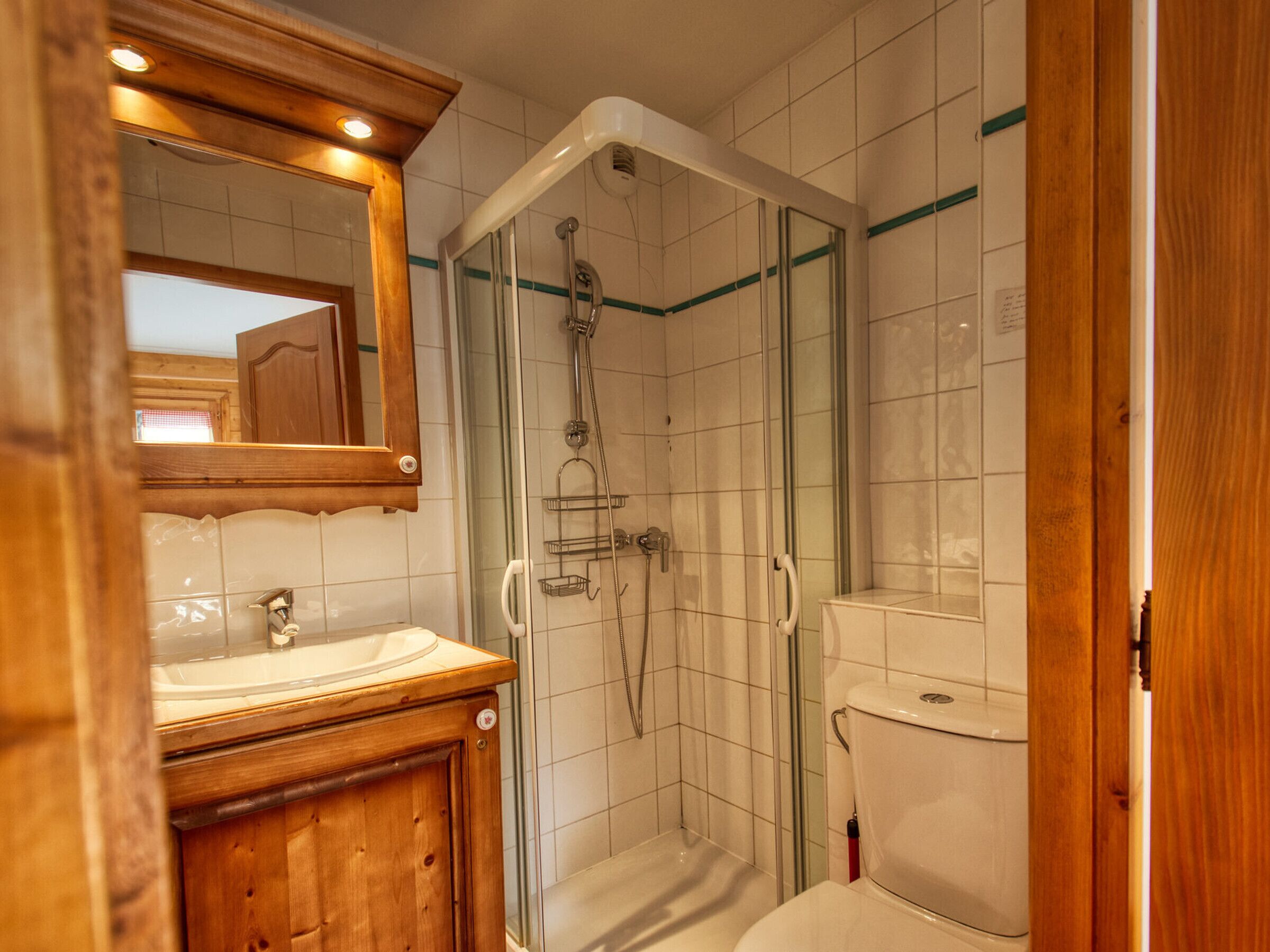 Ein Badezimmer mit einem Holzwaschtisch, einer Glasdusche und einer Toilette.