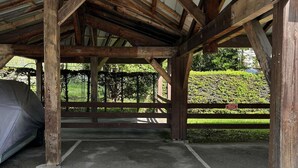 A covered parking area with a wooden structure, a car, and a sign indicating a parking area. - Studio with alcove, sleeps 4 in Demi-Quartier, includes parking (Demi-Quartier)
