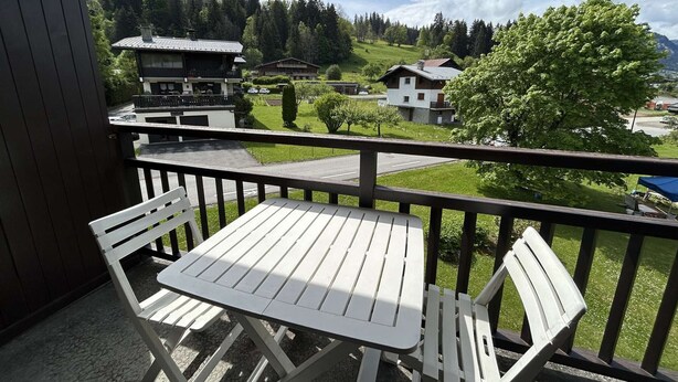 A balcony with a table and chairs, overlooking a residential area with houses and a mountain in the background. - Studio with alcove, sleeps 4 in Demi-Quartier, includes parking (Demi-Quartier)