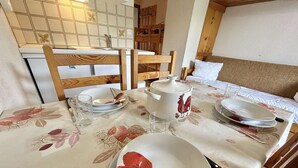 A dining table set with plates, a glass, a fork, a knife, and a pot. - Studio with alcove, sleeps 4 in Demi-Quartier, includes parking (Demi-Quartier)