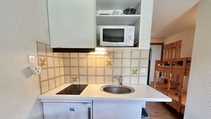 A compact kitchen with a built-in microwave, a sink, and a small refrigerator. - Studio with alcove, sleeps 4 in Demi-Quartier, includes parking (Demi-Quartier)