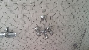 Een douche met een wand met marmerprint en chroombeslag.