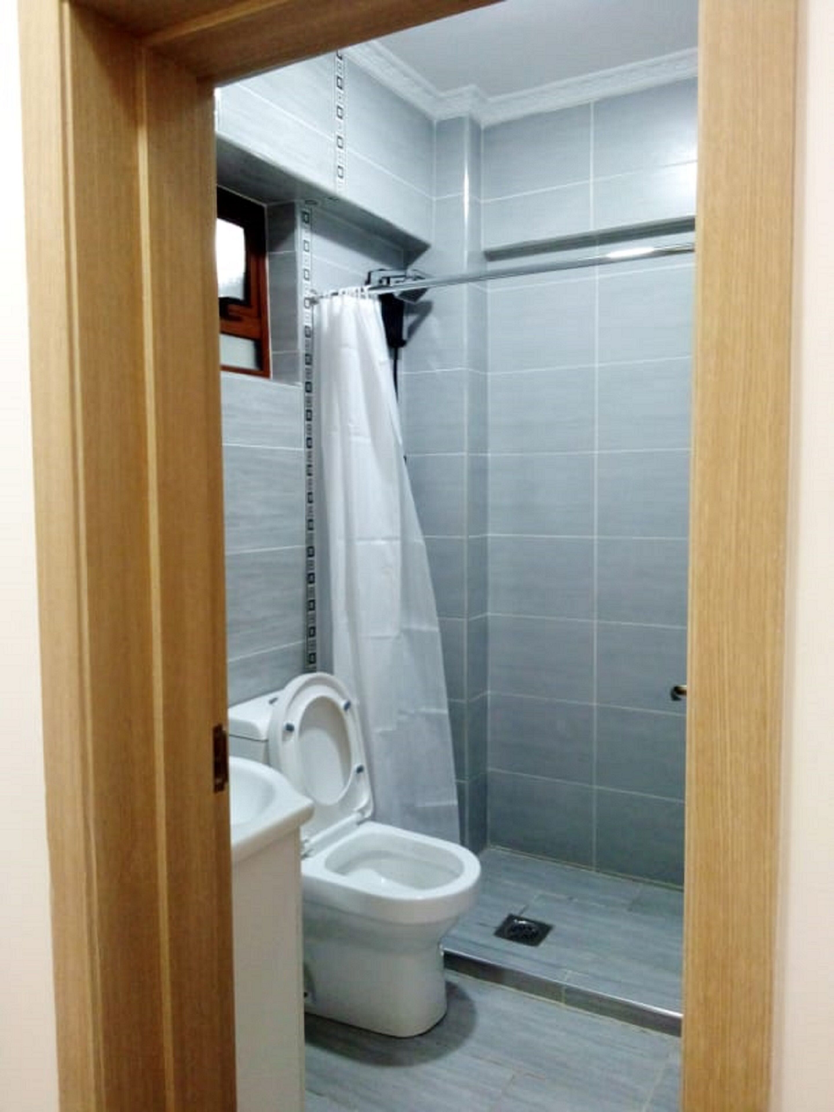 A small, modern bathroom with a toilet, a shower stall, and a tiled floor.
