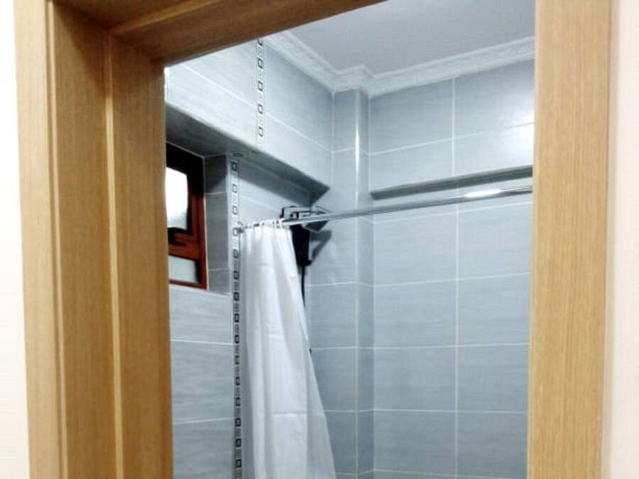 A small, modern bathroom with a toilet, a shower stall, and a tiled floor.