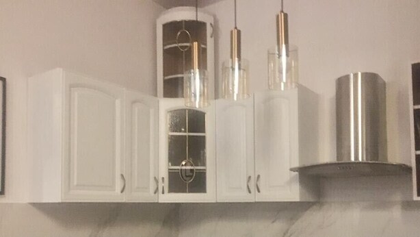A kitchen with white cabinets, a stainless steel range hood, and pendant lights. - Citizen Arts Apartment in a heart of Radom (Radom)