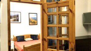 A room with a wooden door, a bed with a red bedspread, and two framed pictures on the wall. - Citizen Arts Apartment in a heart of Radom (Radom)