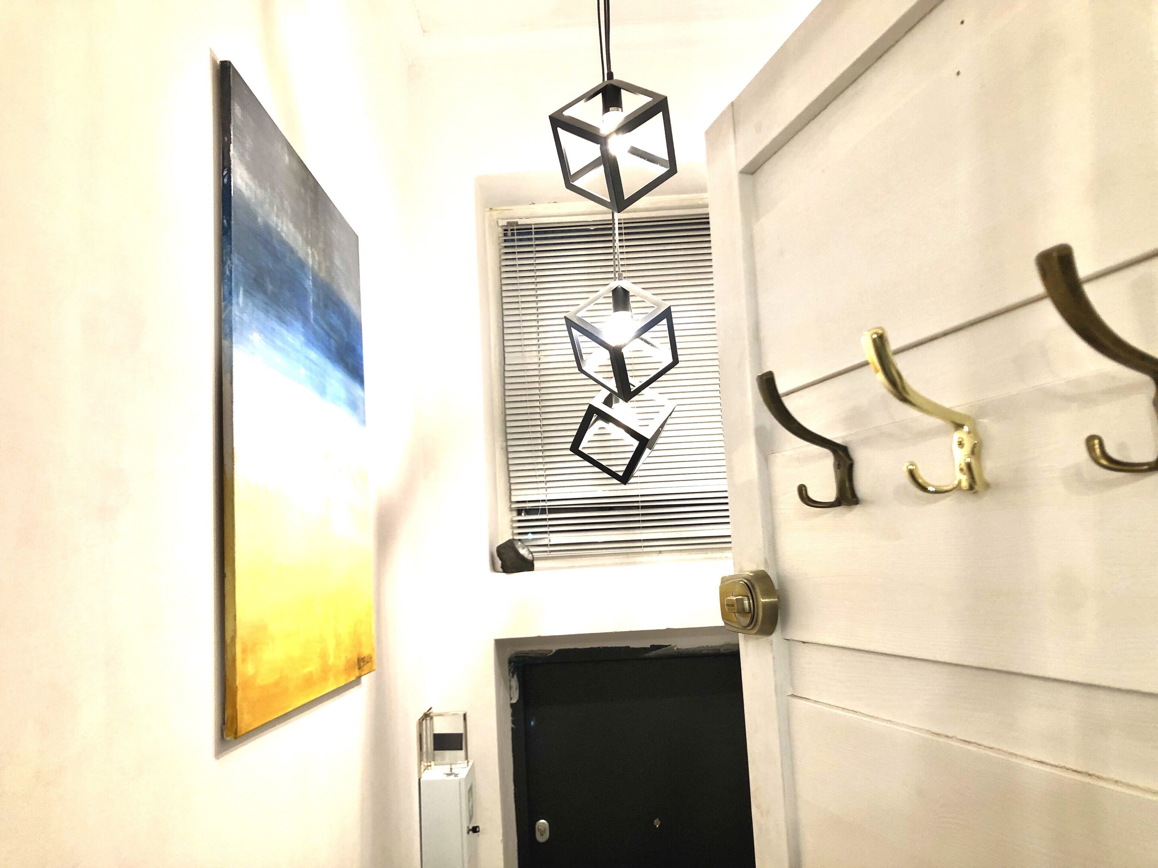 A hallway with a door, a window with blinds, and a wall-mounted light fixture.