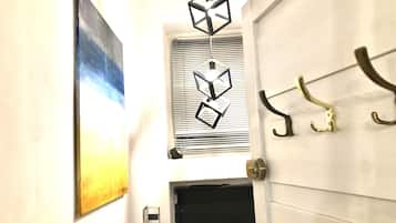 A hallway with a door, a window with blinds, and a wall-mounted light fixture.