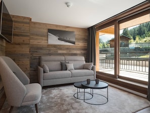 A modern living room with a sofa, armchair, and round coffee table.
