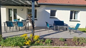 Ein Haus mit Terrasse, Gartenmöbeln und einem Garten.