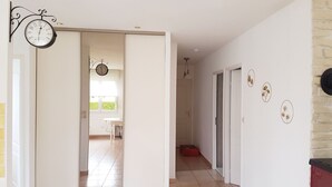 Ein Flur mit einer Tür zu einem Balkon, einer Uhr an der Wand und einem roten Schrank.