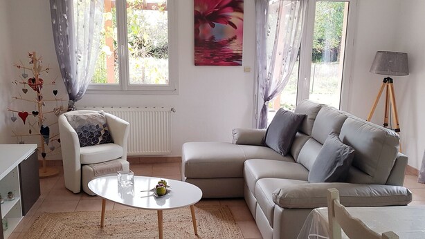 Ein Wohnzimmer mit einem weißen Sofa, einem runden Couchtisch, einem weißen Sessel und einem Gemälde an der Wand.