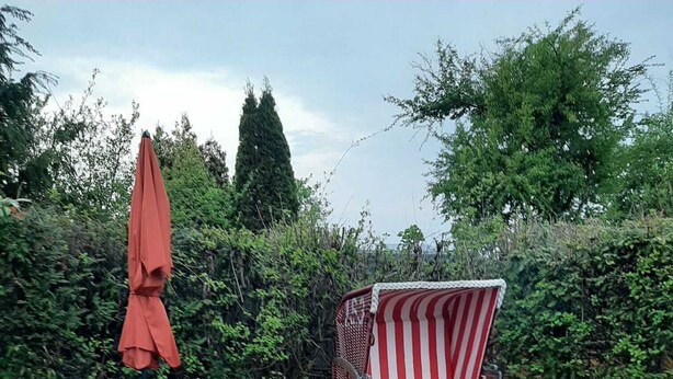Un patio con sillones de madera, una silla a rayas y una chimenea decorativa.