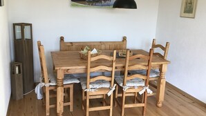 Una mesa de comedor de madera con seis sillas, una lámpara colgante negra y un cuadro en la pared.