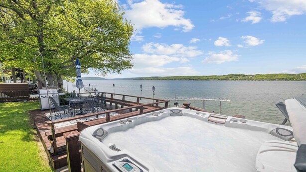 Un bain à remous doté d’un panneau de commande, une terrasse en bois, du mobilier d’extérieur et une vue sur un lac.