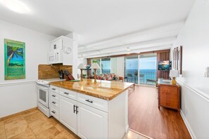 A kitchen with a central island, white cabinetry, and a view to a balcony.
