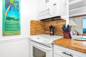 A kitchen with a white stove, oven, and microwave. There is a knife block on the counter.