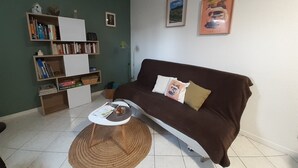 Un salon avec un canapé marron, une table basse blanche et une bibliothèque remplie de livres et d’objets décoratifs.