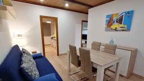 A modern living room with a blue sofa, a dining table with chairs, and a kitchen in the background. - Spacious Apartment (Armilla)