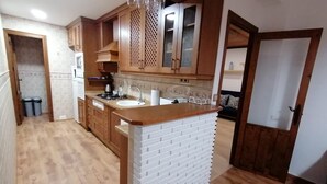 A kitchen with wooden cabinets, a white island, and a tiled backsplash. - Spacious Apartment (Armilla)