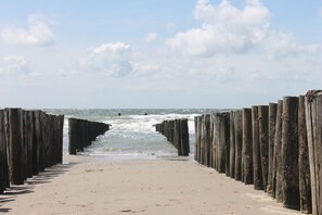 A beach with wooden groynes and a sandy path leading to the sea. - Zon Zee Zoutelande (Zoutelande)
