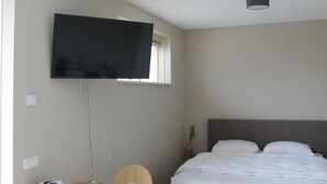 A bedroom with a bed, a mounted television, and a window. - Zon Zee Zoutelande (Zoutelande)