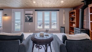 Una sala de estar acogedora con chimenea, una mesa de comedor y vistas al océano a través de amplios ventanales.