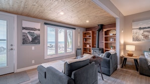 Un salón acogedor con techo de madera, chimenea y vistas al exterior.