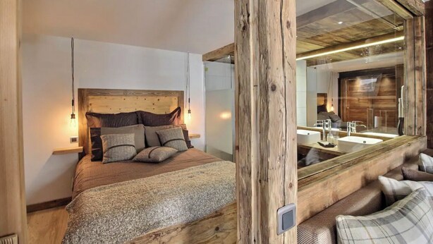 Un dormitorio con cabecera de madera, un espejo grande y una cama con muchos cojines.