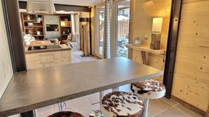 Una cocina moderna con una isla central, armarios de madera y un comedor con mesa y sillas.