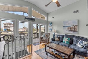 Relax in this stylish living area with a high ceiling, ceiling fan, and large window offering a view of a nearby building.