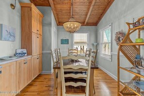 Enjoy meals in this kitchen with a dining table and chairs, wooden cabinets, and a wicker shelf.